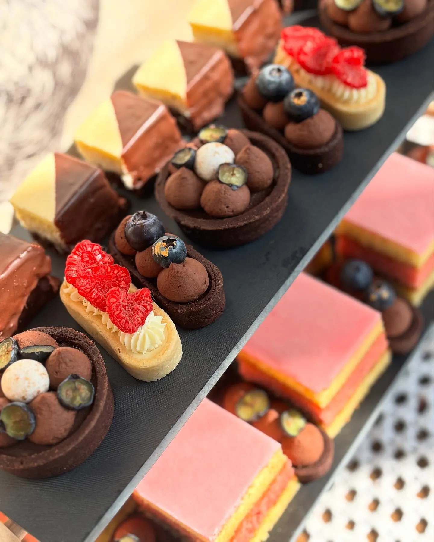 Drevený podnos s drobnými dezertami: éclair, makarónky, ovocné taquito